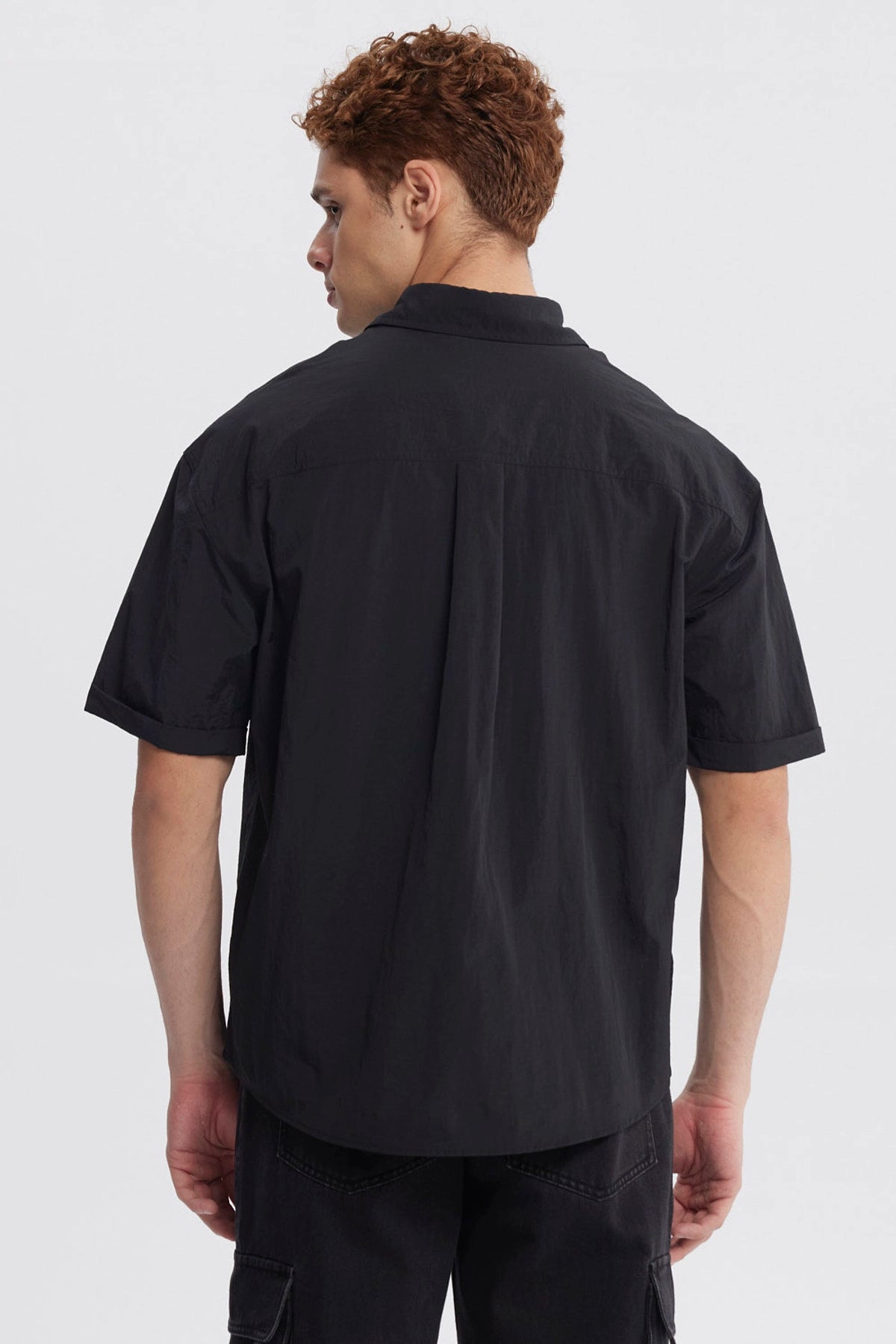 Camisa oversize negra de hombre con doble bolsillo y logo blanco en el pecho estilo casual sin estampa lisa