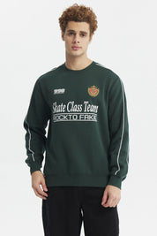 Polerón oversize verde con estampado blanco en el pecho y detalle de escudo en el lado izquierdo estilo deportivo