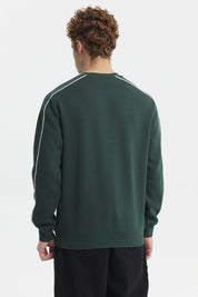Polerón oversize verde con estampado blanco en el pecho y detalle de escudo en el lado izquierdo estilo deportivo