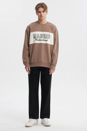 Polerón oversize kaki con cuello redondo y texto 'Madrid Multicultural' en el pecho estilo casual moderno