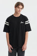 Polera oversize negra para hombre con texto Ability en el pecho y rayas blancas en mangas estilo casual