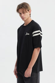 Polera oversize negra para hombre con texto Ability en el pecho y rayas blancas en mangas estilo casual