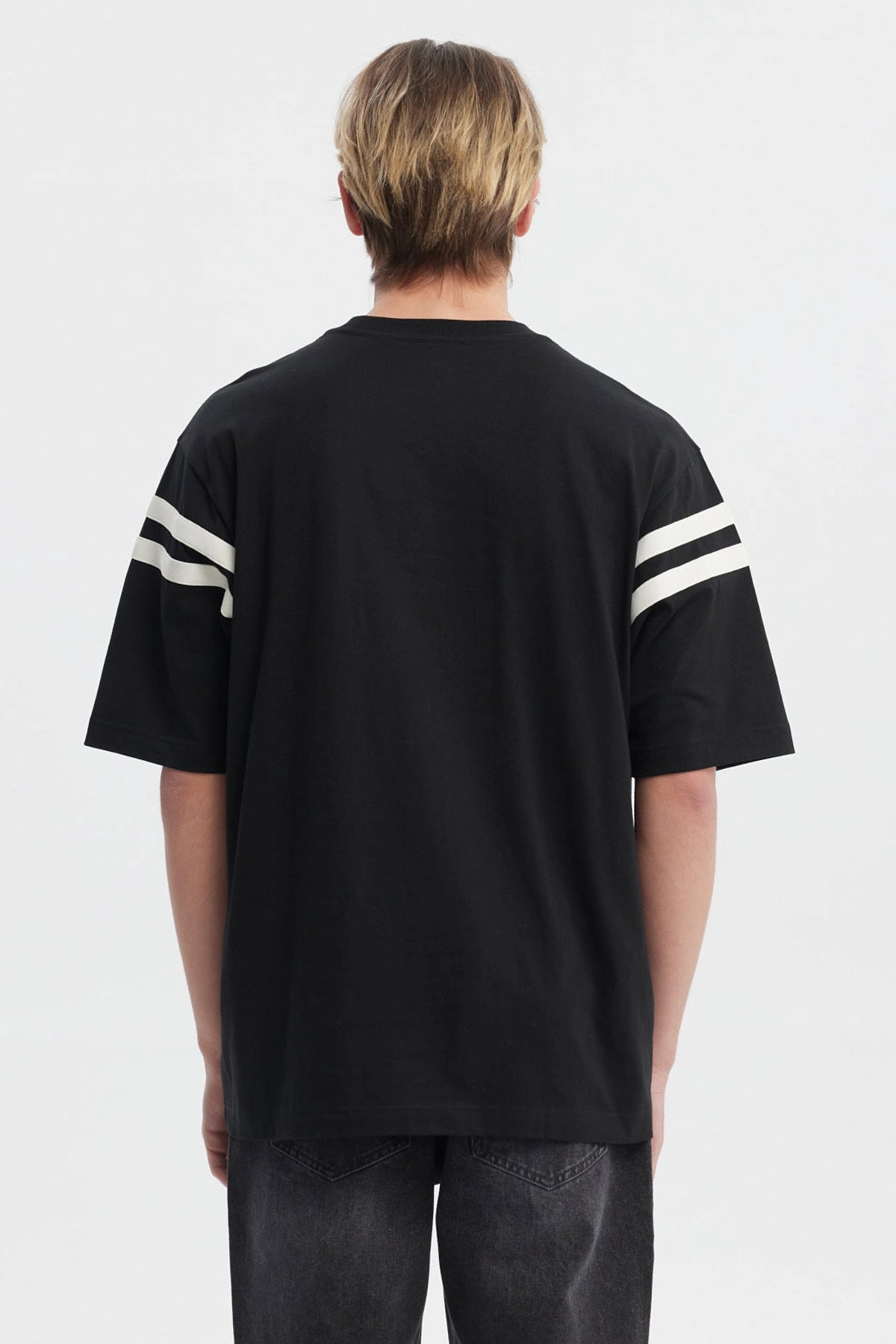 Polera oversize negra para hombre con texto Ability en el pecho y rayas blancas en mangas estilo casual