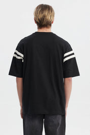 Polera oversize negra para hombre con texto Ability en el pecho y rayas blancas en mangas estilo casual