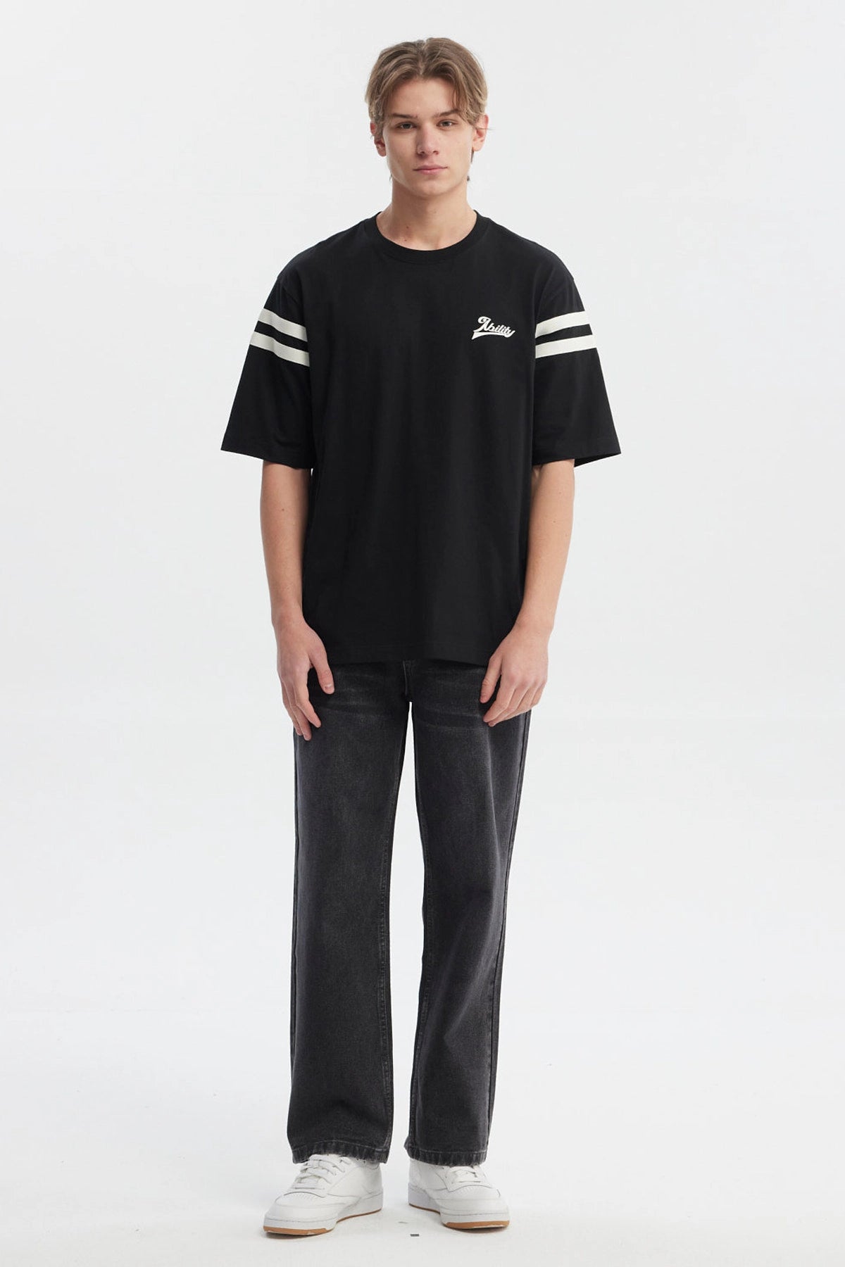 Polera oversize negra para hombre con texto Ability en el pecho y rayas blancas en mangas estilo casual