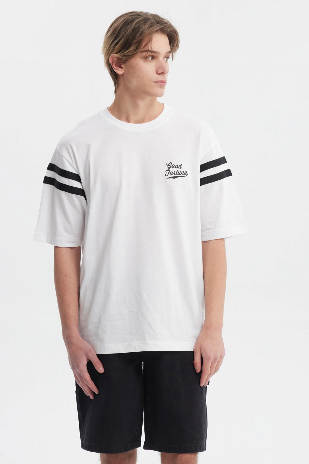 Polera oversize blanca con texto Good Fortune en el pecho rayas negras en las mangas estilo casual y moderno