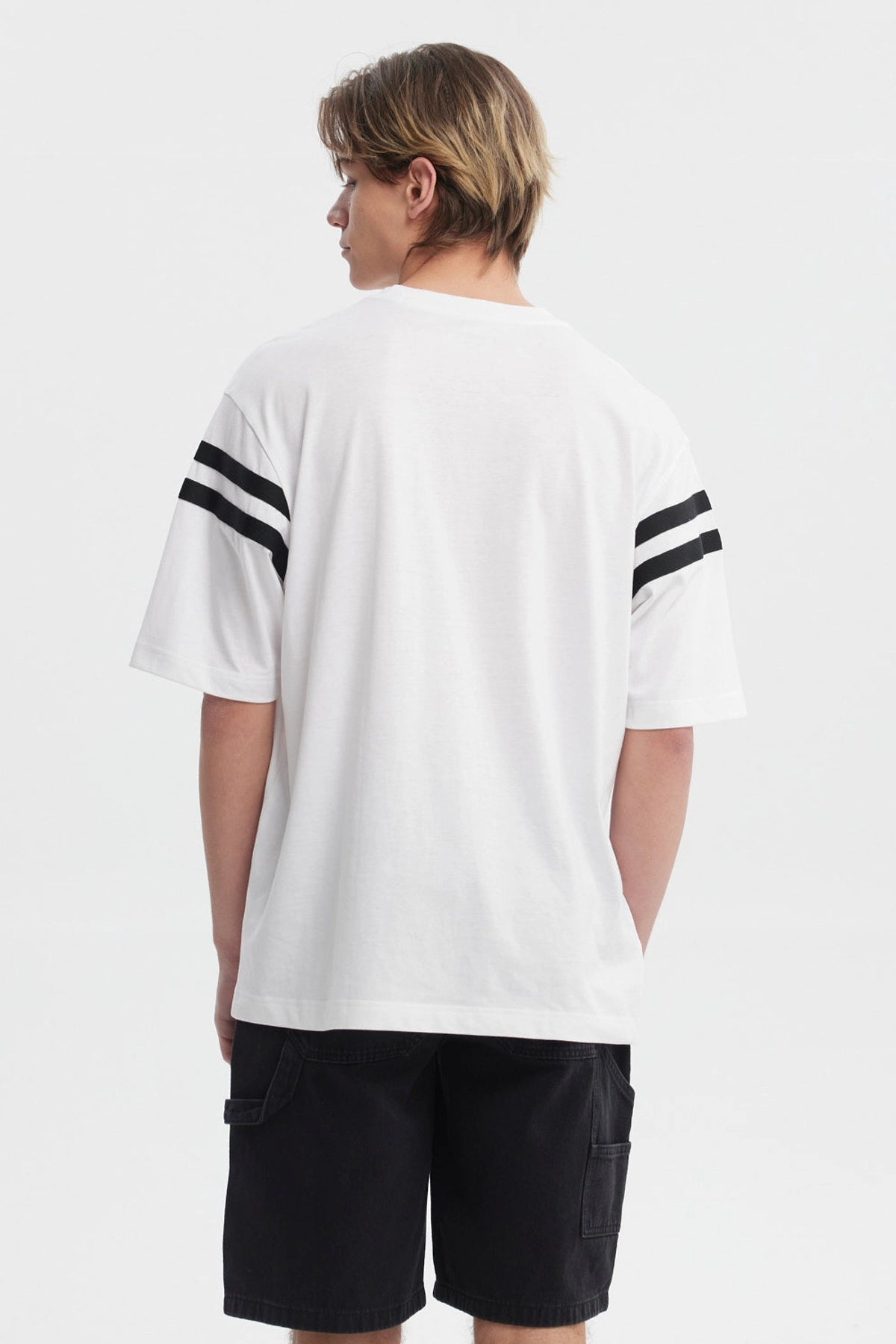 Polera oversize blanca con texto Good Fortune en el pecho rayas negras en las mangas estilo casual y moderno