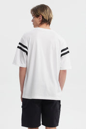 Polera oversize blanca con texto Good Fortune en el pecho rayas negras en las mangas estilo casual y moderno