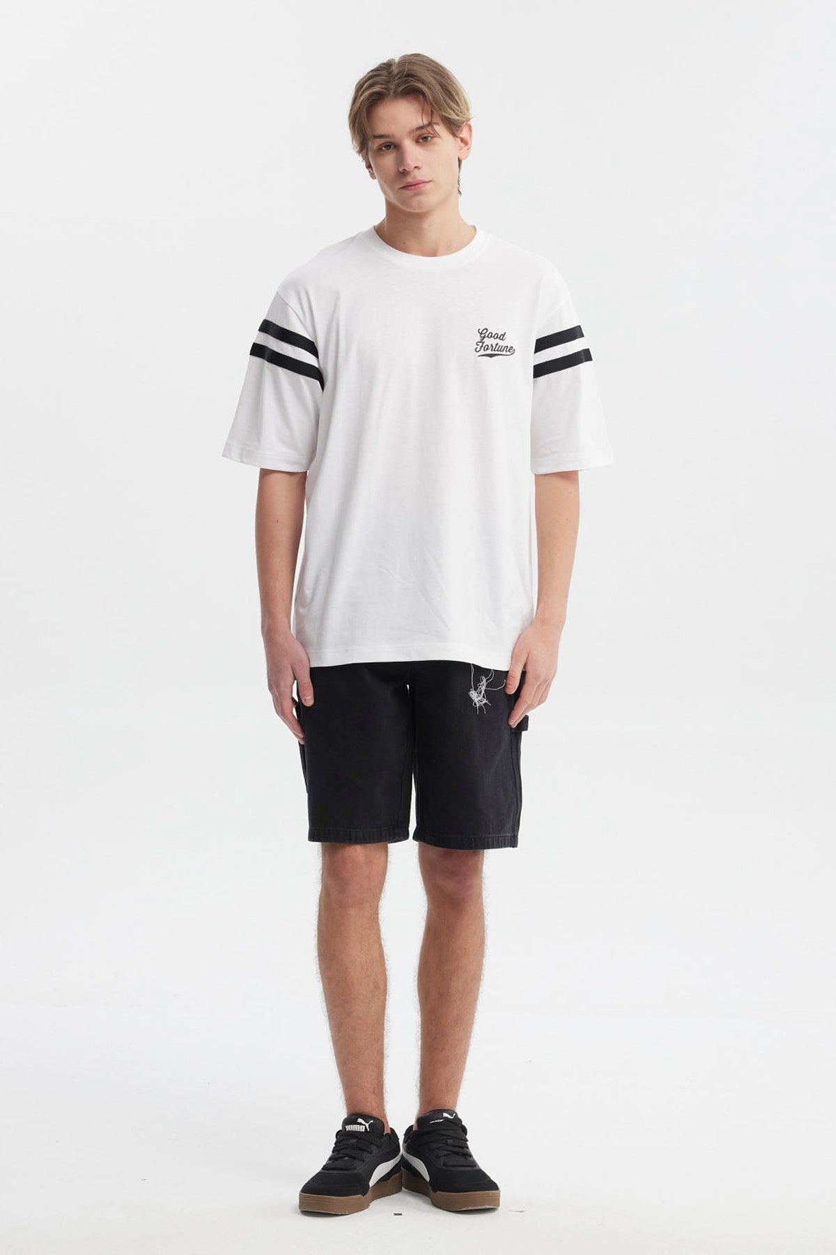 Polera oversize blanca con texto Good Fortune en el pecho rayas negras en las mangas estilo casual y moderno
