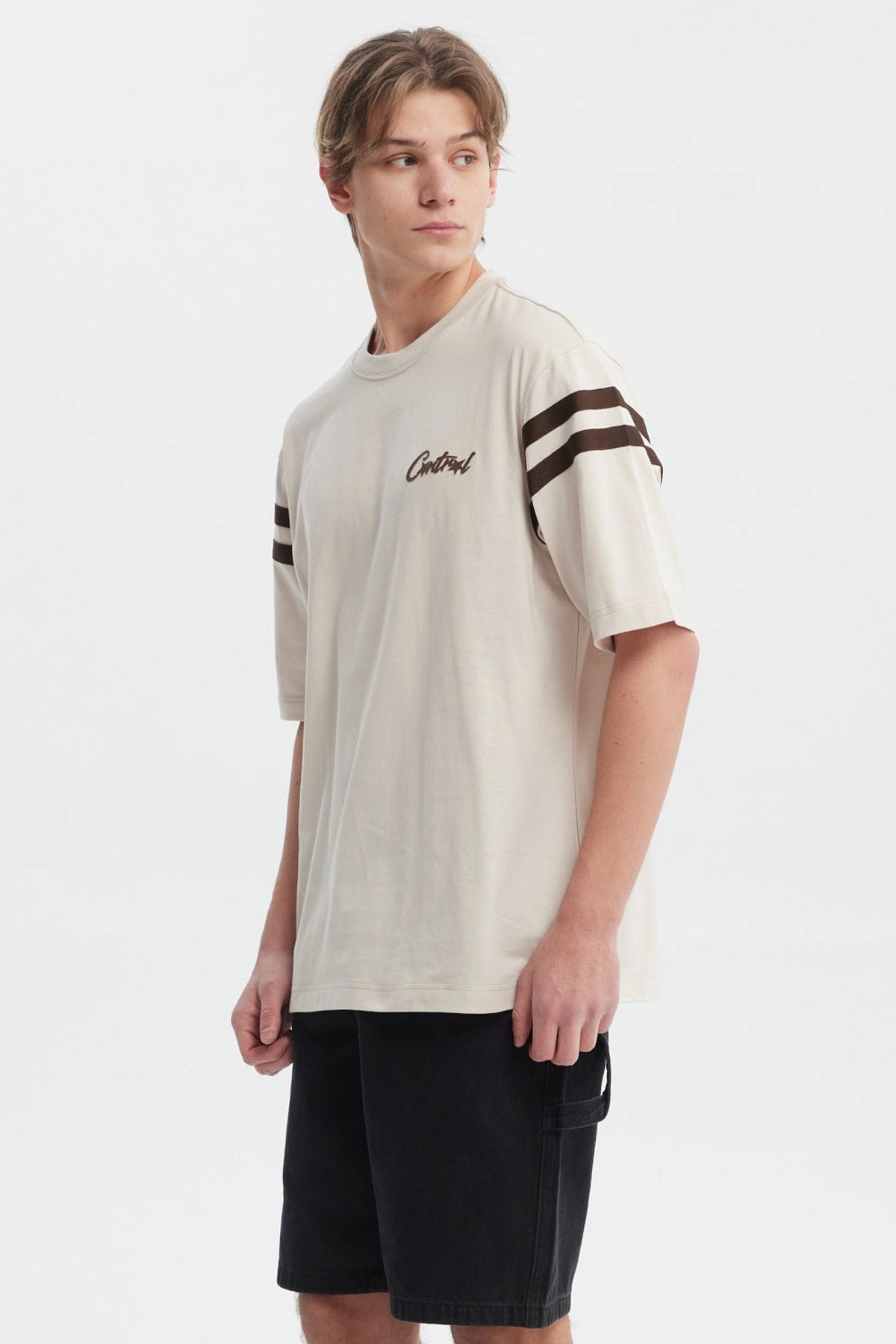 Polera oversize beige con logo "Critical" en el pecho estilo urbano y rayas marrones en las mangas