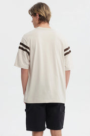 Polera oversize beige con logo "Critical" en el pecho estilo urbano y rayas marrones en las mangas