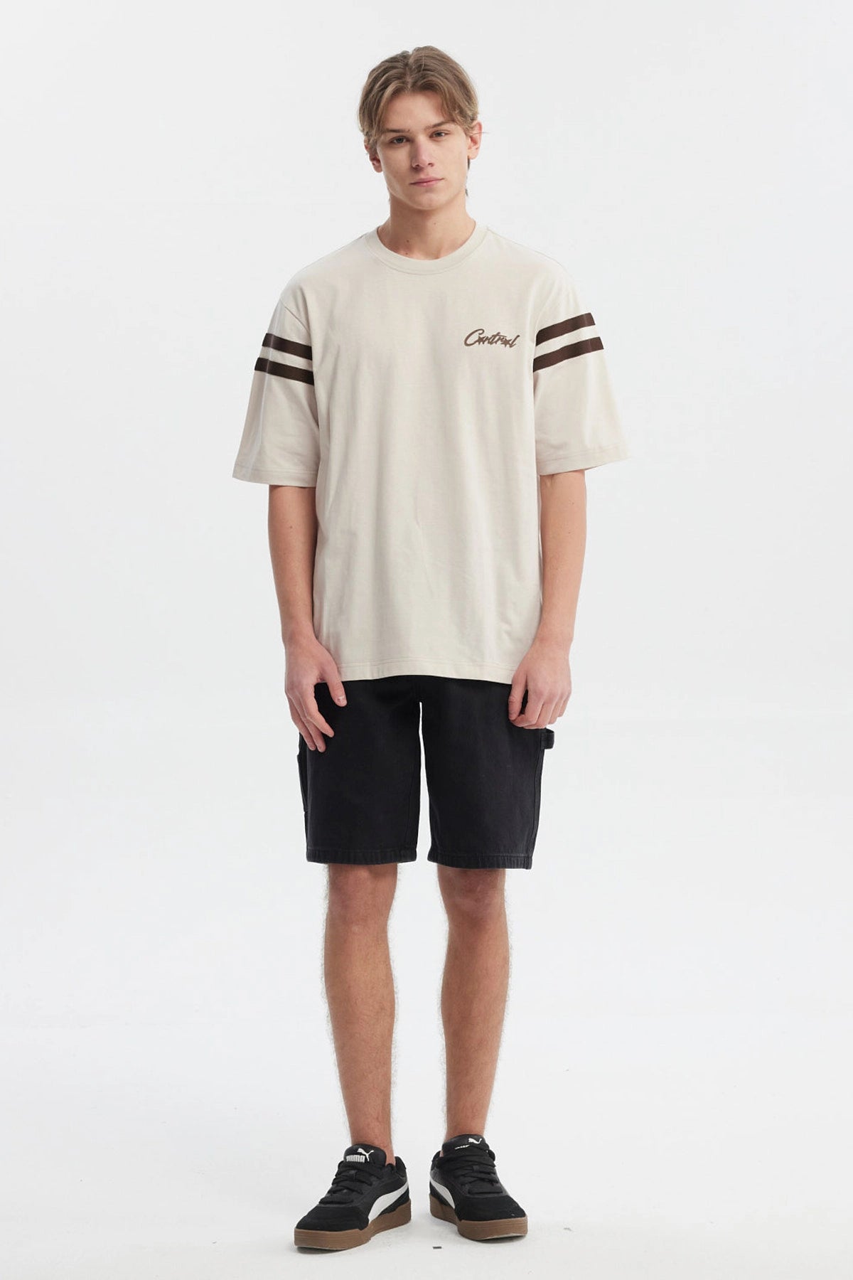 Polera oversize beige con logo "Critical" en el pecho estilo urbano y rayas marrones en las mangas