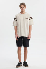 Polera oversize beige con logo "Critical" en el pecho estilo urbano y rayas marrones en las mangas