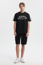 Polera negra slim para hombre con texto Growth Move and Rise en el pecho estilo universitario y líneas blancas en los hombros