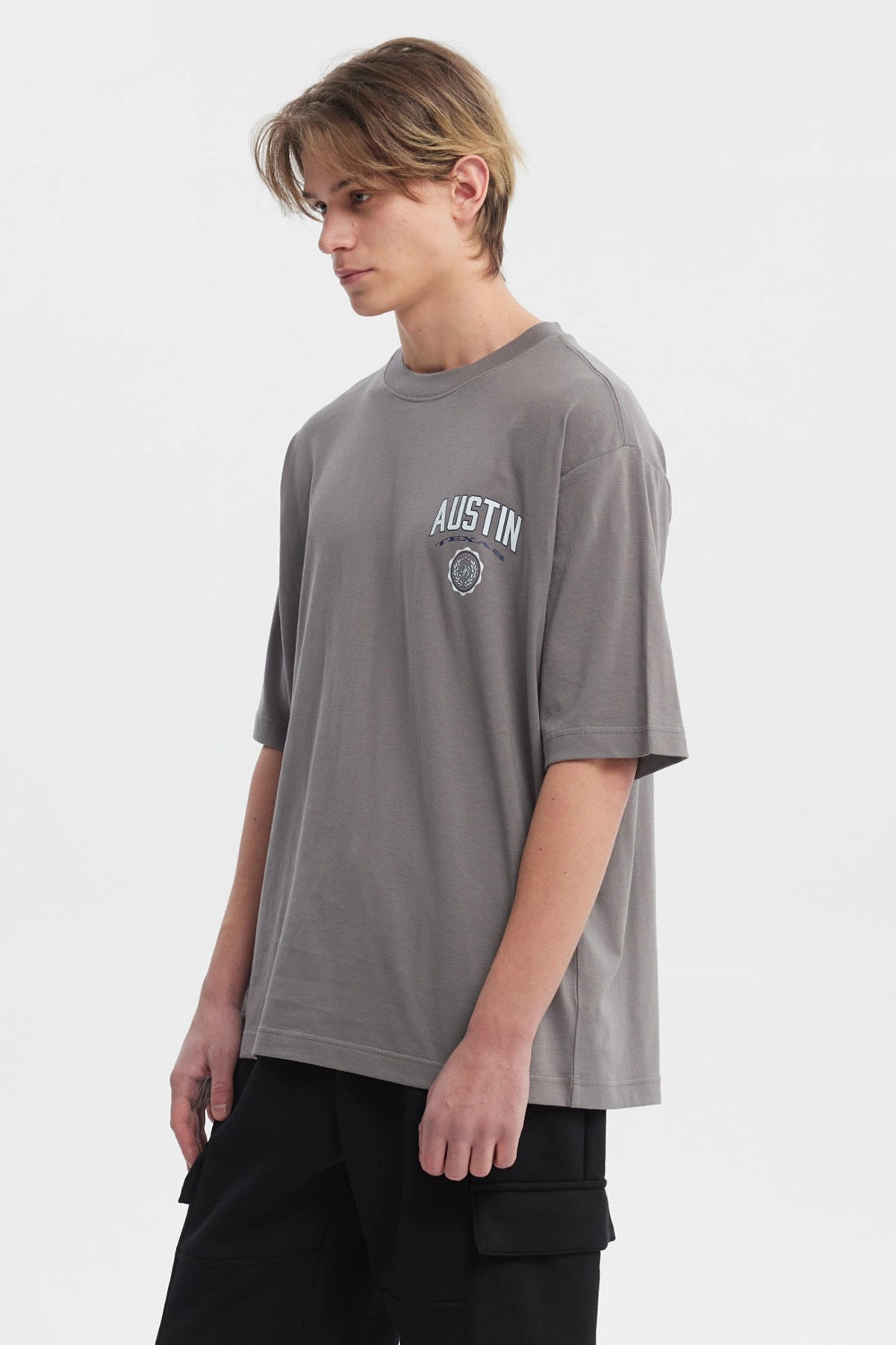 Polera hombre slim gris con estampa frontal de texto AUSTIN y escudo pequeño estilo casual
