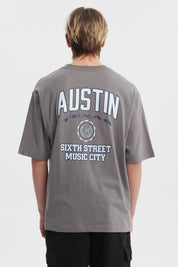 Polera hombre slim gris con estampa frontal de texto AUSTIN y escudo pequeño estilo casual