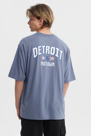 Polera hombre slim azul piedra con texto blanco Detroit 1839 Motown en el pecho estilo casual moderno sin estampa adicional
